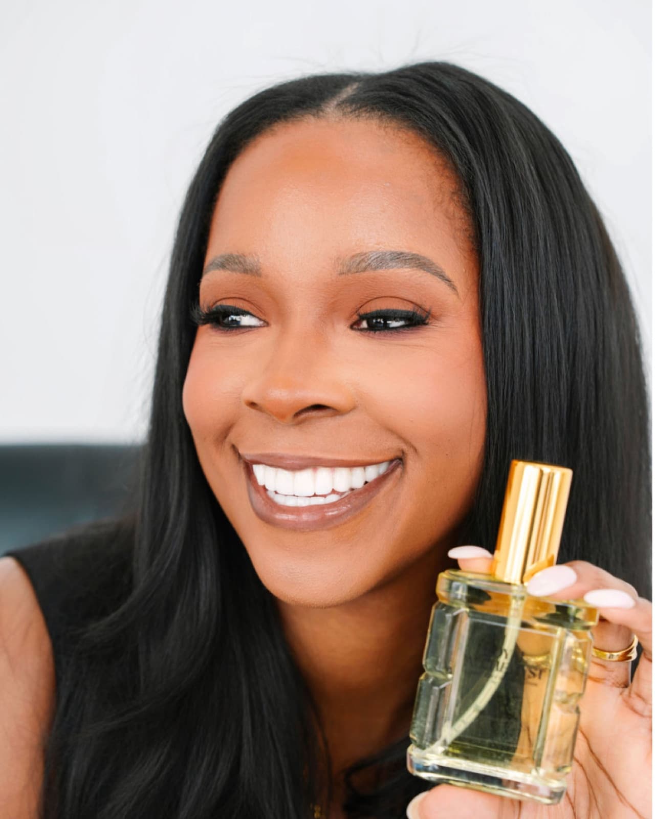 Christin Bradley, founder of Royal Alchemyst, smiling and holding a body oil